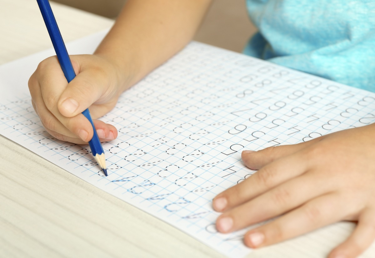 Seorang anak sedang belajar menulis angka pada kertas soal latihan